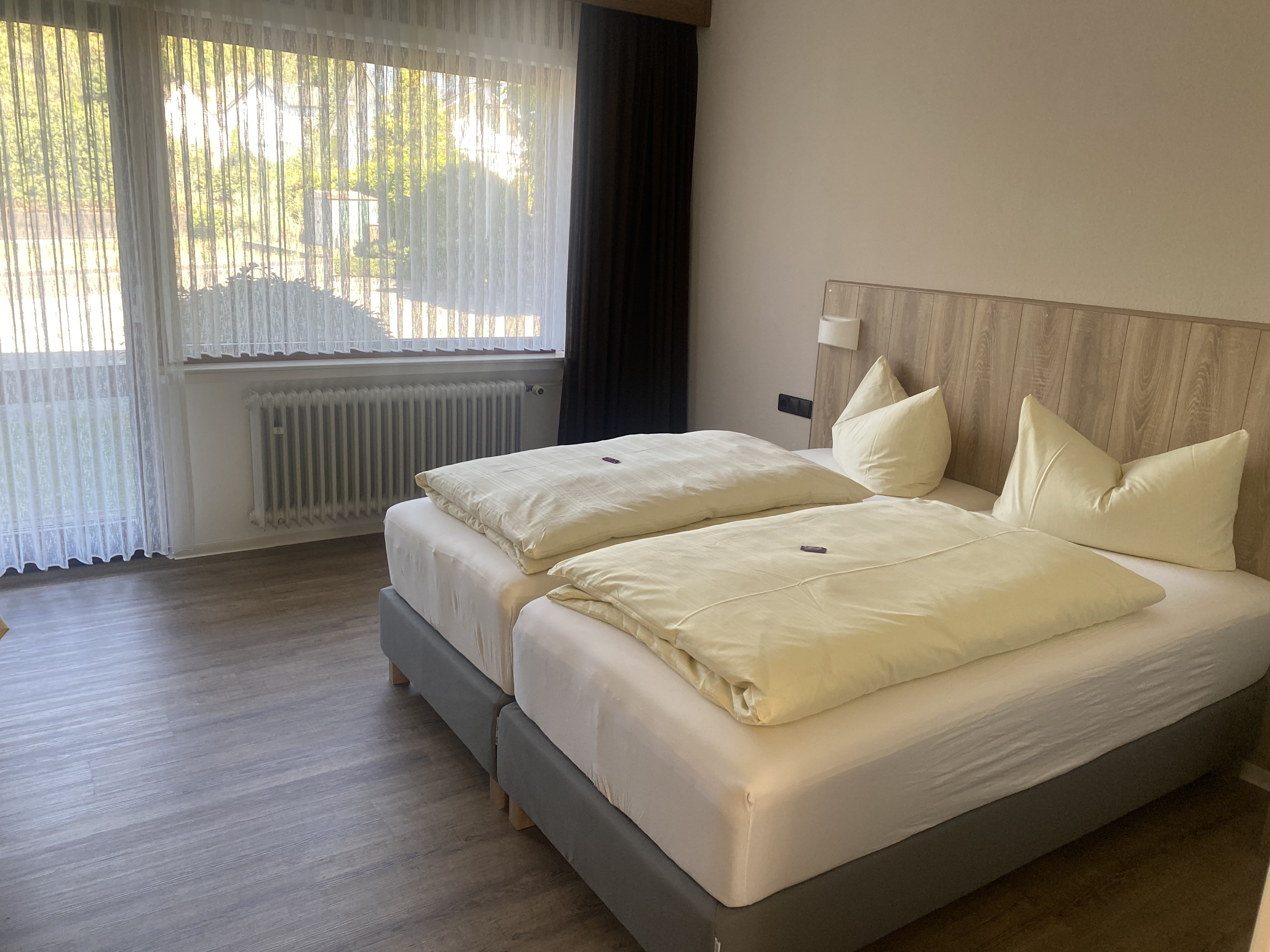 Doppelzimmer mit hellem Holz-Kopfteil und großem Fenster